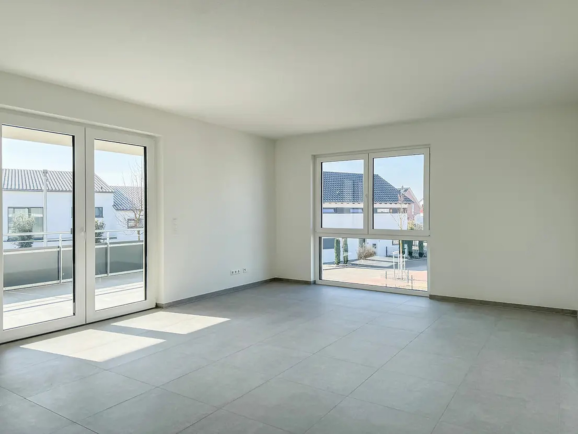 Wohnzimmer mit bodentiefen Fenstern und Zugang zum Balkon